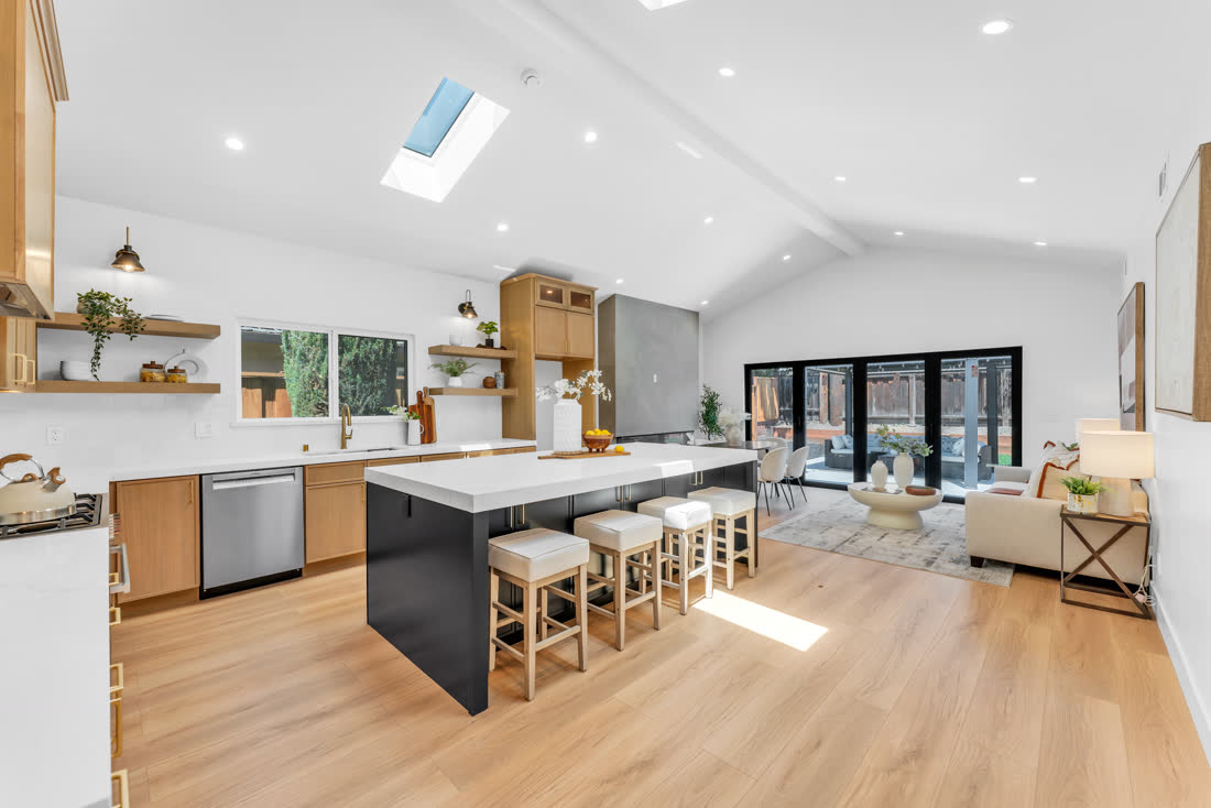 Vaulted great room, skylight above a black waterfall island and open kitchen