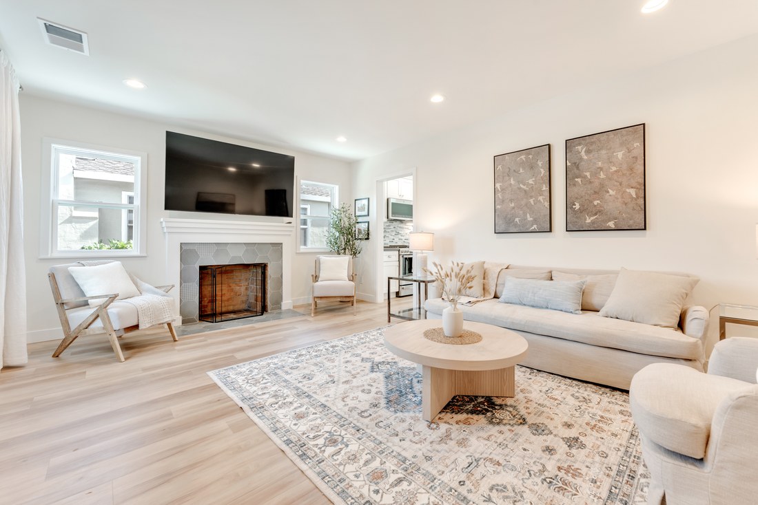 Living room with a tiled fireplace, a low cream sofa and light wood floors